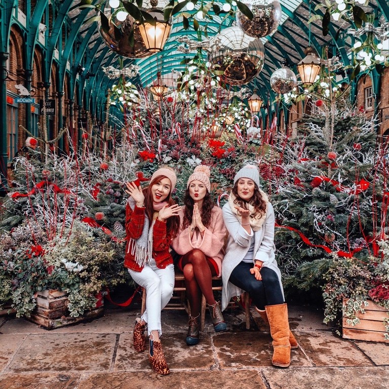 Girls sitting by Christmas trees in Covent Garden